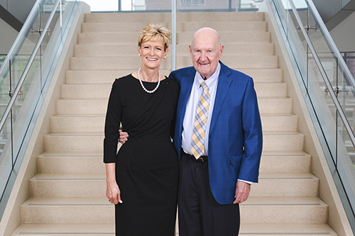 Man and woman stand on stairs in Hawks Hall.