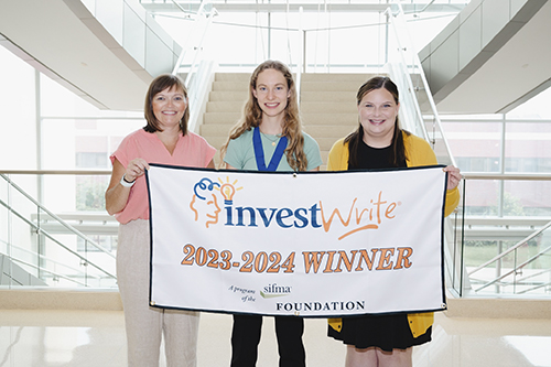 Two women stand with student and giant check