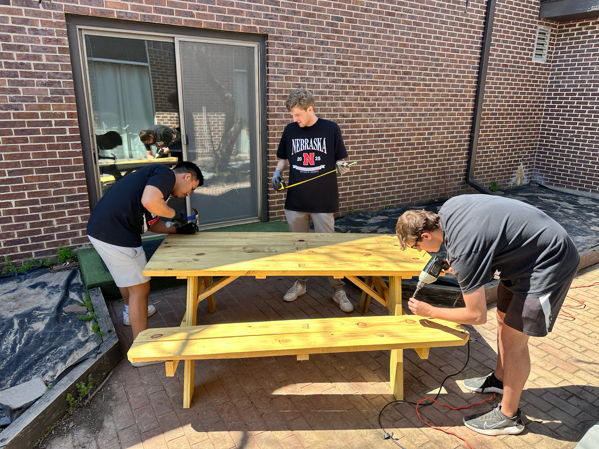 Three students assemble a picnic table