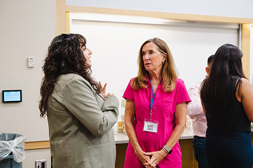 Two women chat at conference.