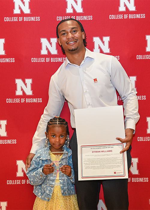 Man and little girl pose with award.