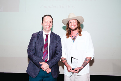 man in hat accepts award.