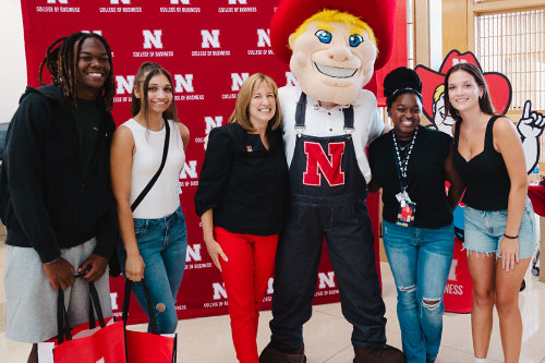 Four students pose with Dean Kathy Farrell and Herbie Husker at the Back to School Bash.