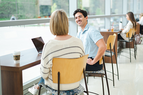 A male and female student talk about their individual talents over coffee.